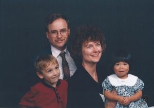 Parents with two kids in front of black backdrop