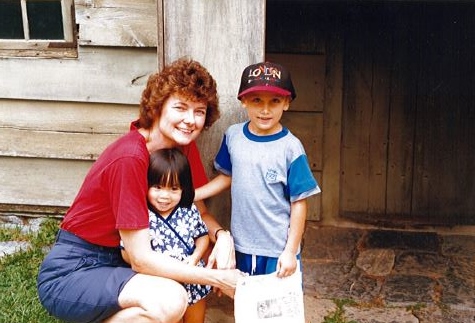 Mom with two kids, son wearing baseball hat